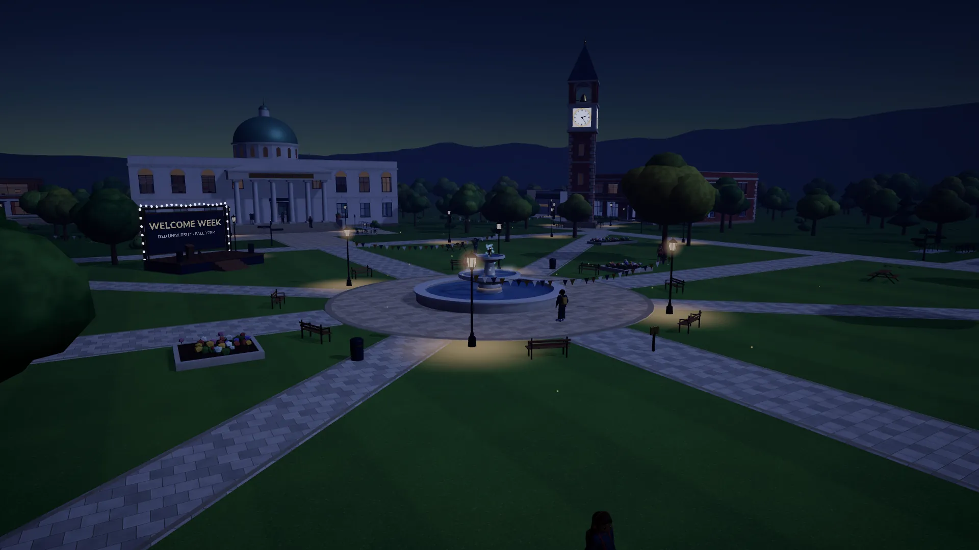 D2D University at night: lamps along the quad's paths, the fountain and the clock tower lit against a deep blue sky.
